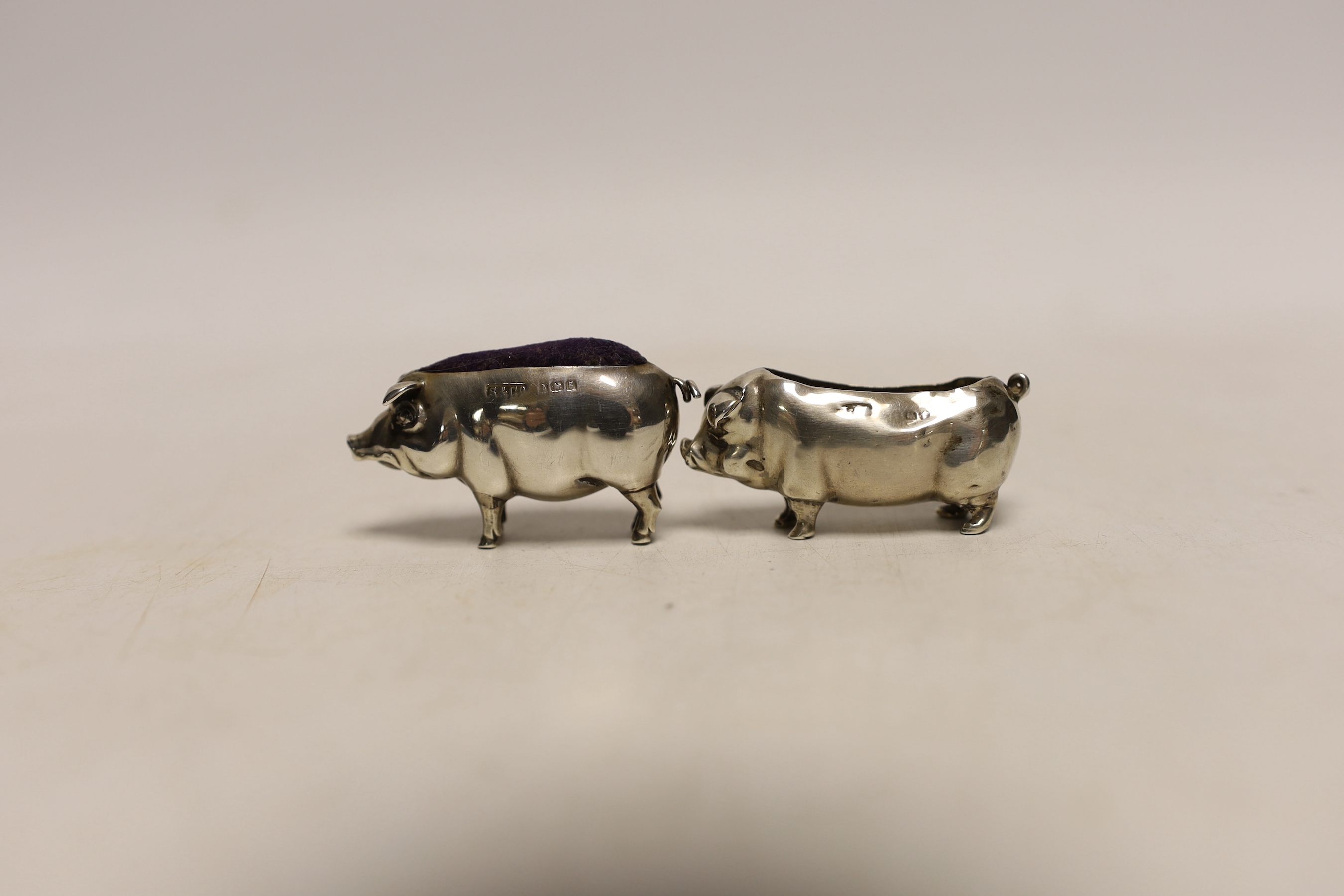 An Edwardian novelty silver pin cushion, modelled as a pig, Sydney & Co, Birmingham, 1906, length 49mm, together with one other silver pig pin cushion, marks rubbed and lacking cushion.